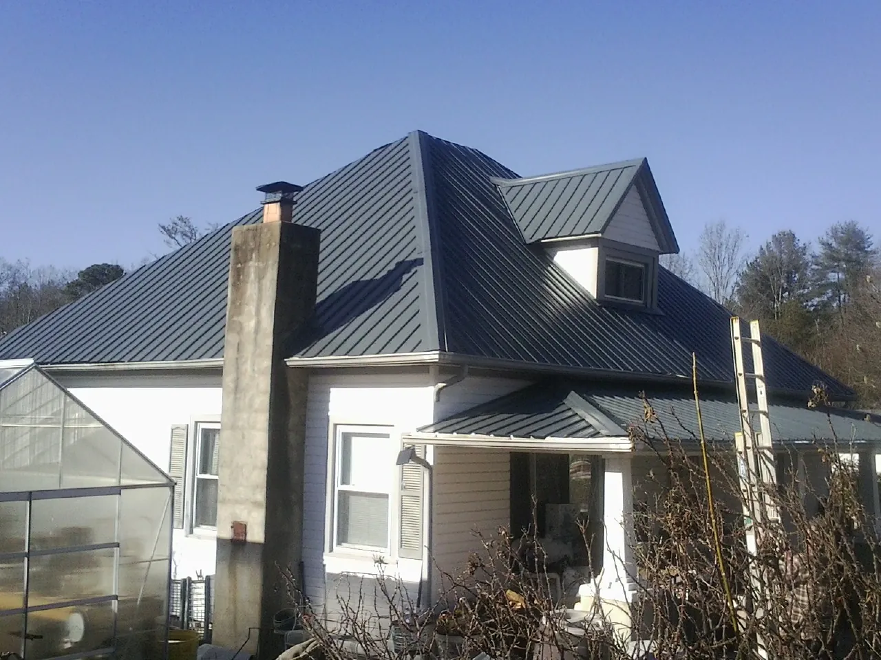 Dark blue standing seam metal roof on a white farmhouse with dormer — Slate & Tile Roof Repair by Roofing Brothers in Rincon