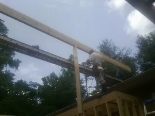 Carpenter setting a ridge beam over a new addition frame — Ice Dam Removal by Roofing Brothers in Rincon