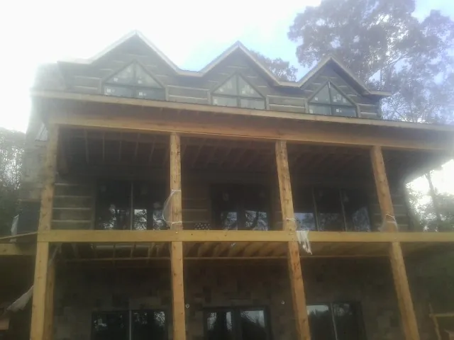 Dormers and porch framing on a large log home under construction — Roof Coating work by our crew in Rincon