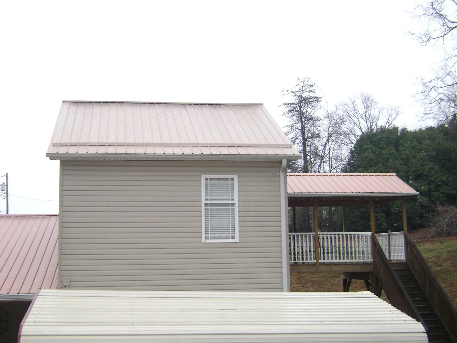 Tan metal roofs on a two story addition and attached porch, from a Roof Replacement job in Rincon